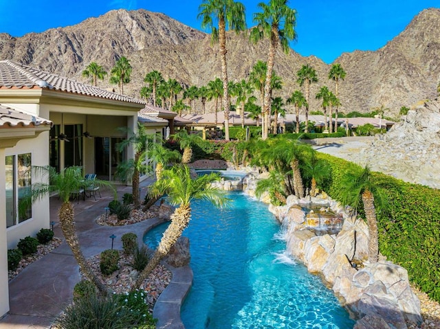 view of pool with a mountain view, a patio area, ceiling fan, and pool water feature