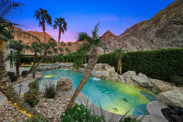 pool at dusk with pool water feature and a mountain view