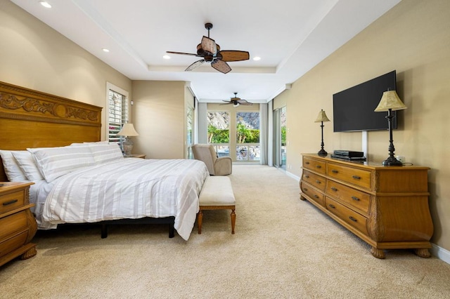 bedroom with ceiling fan, light colored carpet, a raised ceiling, and access to outside