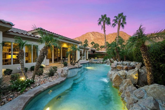 pool at dusk with a mountain view and pool water feature