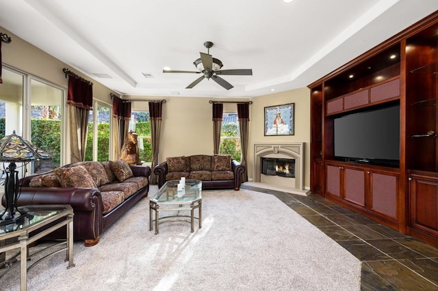 living room featuring ceiling fan and a tray ceiling