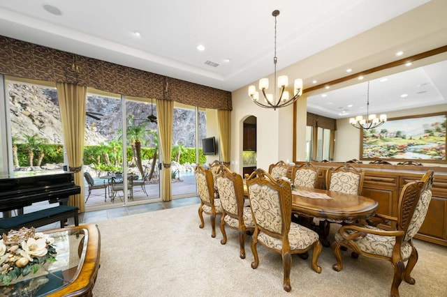 dining space with an inviting chandelier, light tile patterned floors, and a tray ceiling