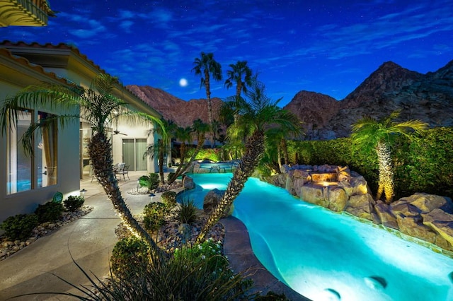 view of pool with a hot tub, a mountain view, and a patio