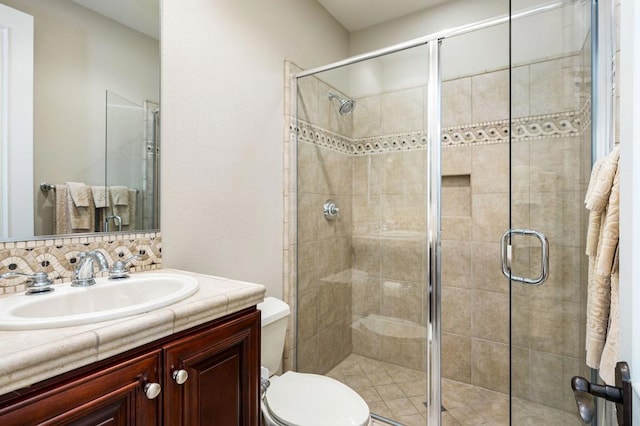 bathroom with vanity, toilet, decorative backsplash, and a shower with door