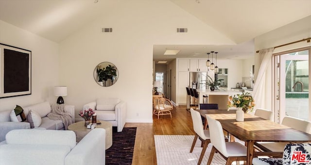 dining area featuring hardwood / wood-style flooring and high vaulted ceiling