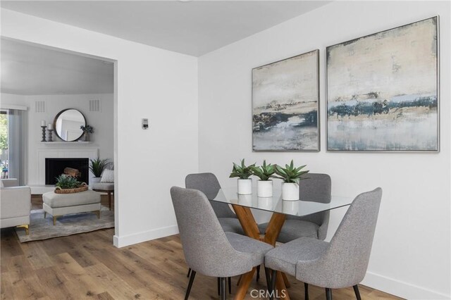 750 Chorro St Unit 5, San Luis Obispo, CA 93401 - dining room featuring baseboards, wood finished floors, and a fireplace with raised hearth