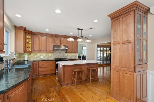 kitchen with washer and dryer, a kitchen island, pendant lighting, sink, and gas range