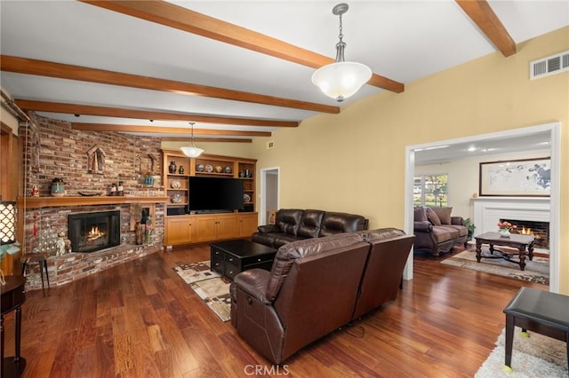 living room with a brick fireplace, dark wood-type flooring, built in features, and beamed ceiling