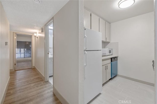 kitchen with white cabinetry, white appliances, and a textured ceiling