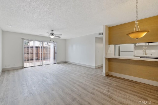 unfurnished living room with hardwood / wood-style flooring, a textured ceiling, and ceiling fan