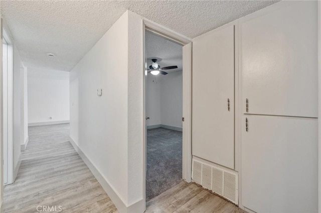 hall featuring a textured ceiling and light hardwood / wood-style flooring