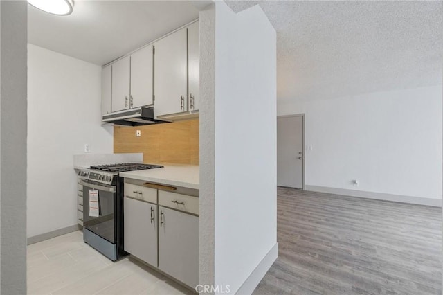 kitchen with gas range, white cabinetry, and a textured ceiling