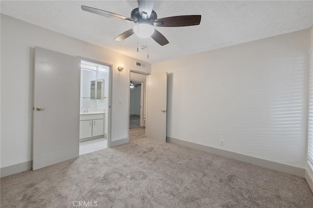 unfurnished bedroom with sink, connected bathroom, light colored carpet, and ceiling fan