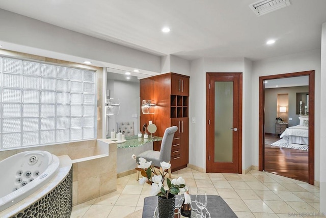 bathroom with a relaxing tiled tub and tile patterned flooring