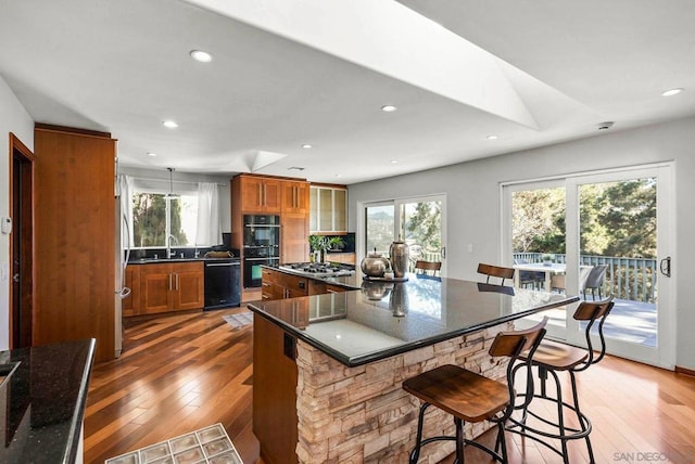 kitchen featuring black appliances, a center island, a kitchen bar, sink, and dark hardwood / wood-style floors