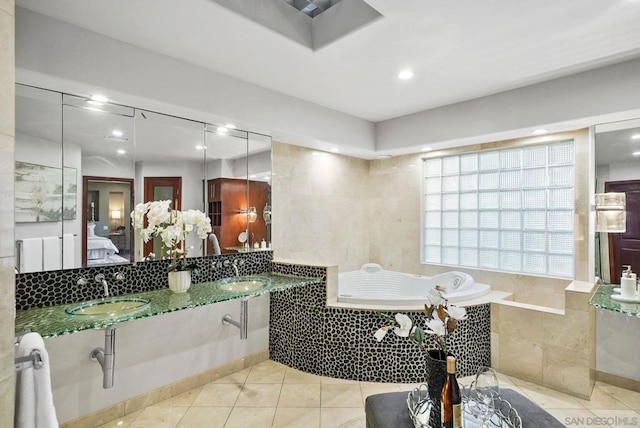 bathroom with tiled bath, tile patterned flooring, and double sink