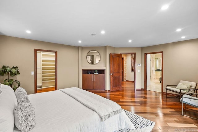 bedroom with ensuite bath and hardwood / wood-style floors