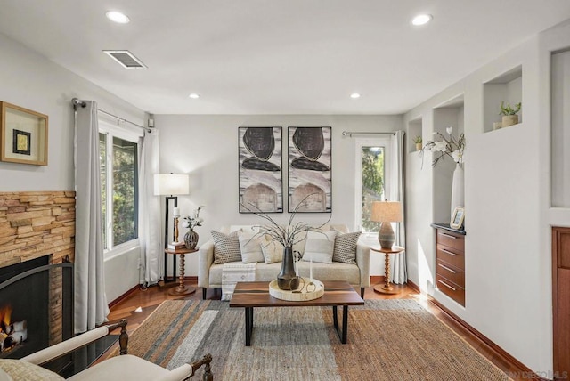 living room featuring a stone fireplace and hardwood / wood-style flooring