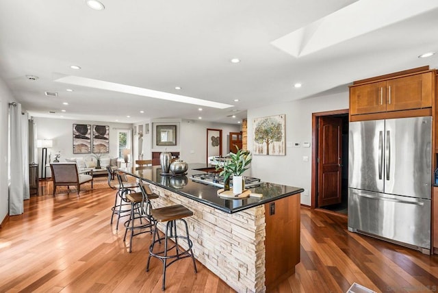 kitchen with a kitchen island, a kitchen bar, dark hardwood / wood-style flooring, a skylight, and stainless steel appliances