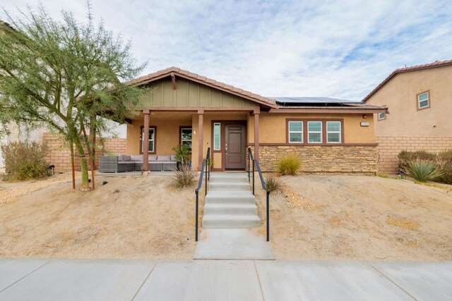 view of front of home with central AC unit, an outdoor hangout area, and solar panels