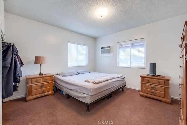 bedroom with a textured ceiling, carpet floors, and an AC wall unit