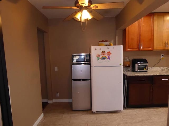 kitchen featuring ceiling fan, light stone countertops, light tile patterned floors, stainless steel fridge, and white refrigerator