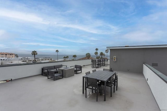 view of patio with a water view and an outdoor living space with a fire pit