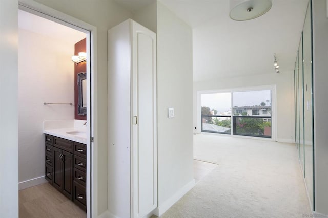 corridor with sink and light carpet