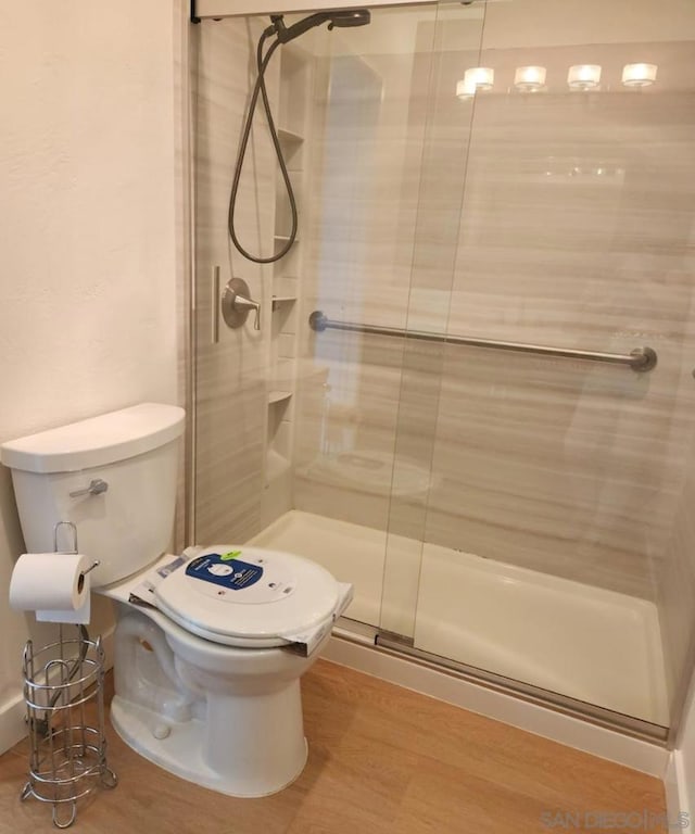 bathroom featuring wood-type flooring, an enclosed shower, and toilet