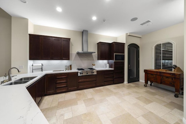 kitchen featuring tasteful backsplash, stainless steel gas stovetop, sink, built in microwave, and wall chimney exhaust hood