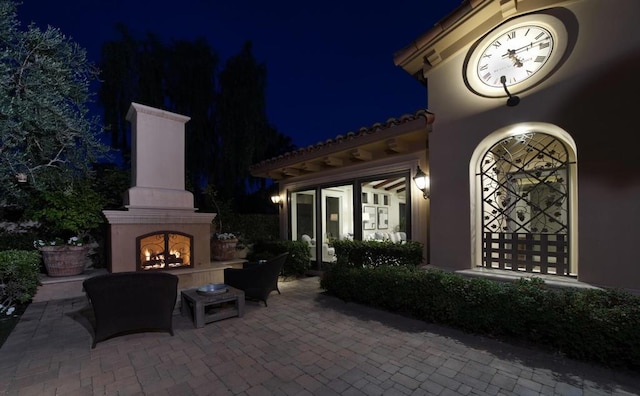 patio at twilight featuring an outdoor fireplace