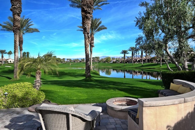 view of home's community with a patio area, a water view, an outdoor fire pit, and a yard