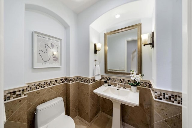 bathroom with toilet and tile walls