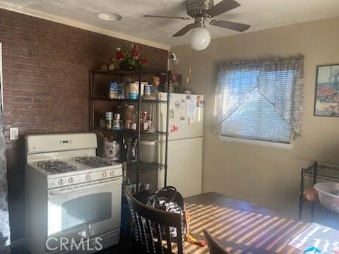 kitchen with ceiling fan, brick wall, and white appliances