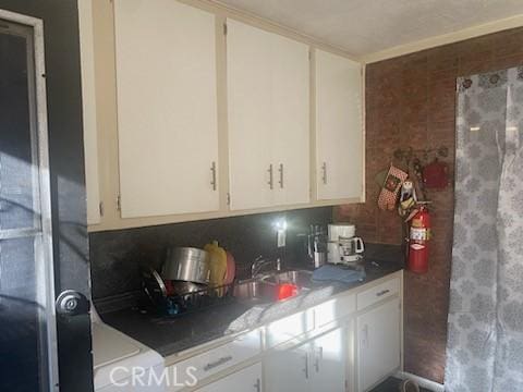 kitchen with white cabinets, backsplash, and sink