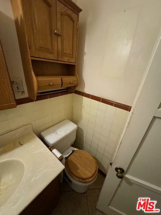 bathroom featuring sink, tile walls, and toilet