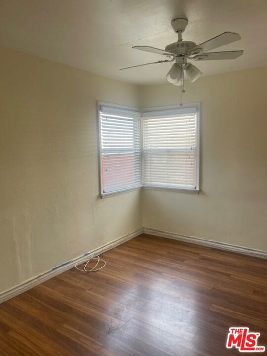 empty room featuring ceiling fan and dark wood-type flooring