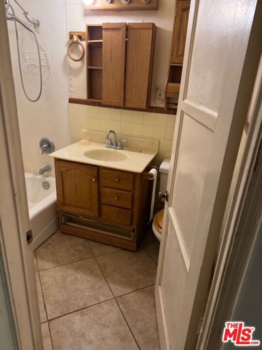 full bathroom featuring toilet, vanity, tile patterned flooring, backsplash, and shower / washtub combination