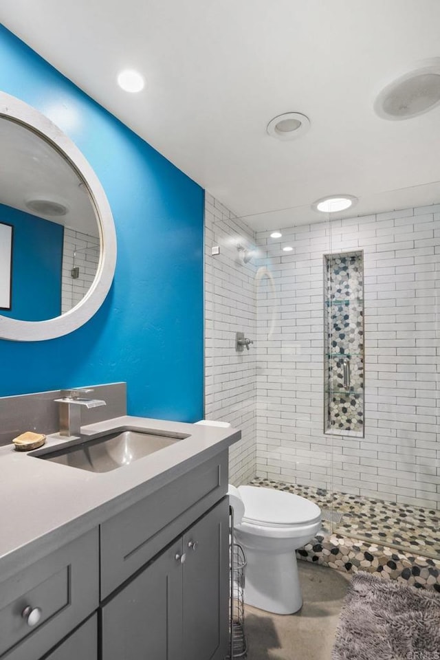 bathroom with vanity, toilet, and tiled shower