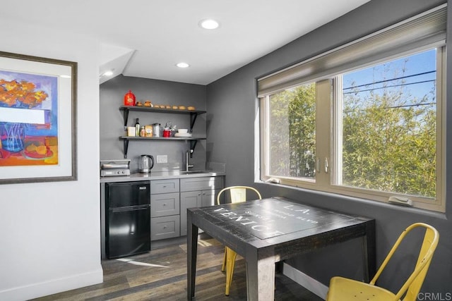 bar featuring black refrigerator, sink, dark hardwood / wood-style flooring, and gray cabinetry