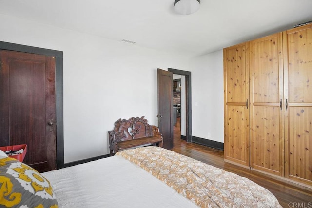 bedroom with dark hardwood / wood-style flooring and a closet