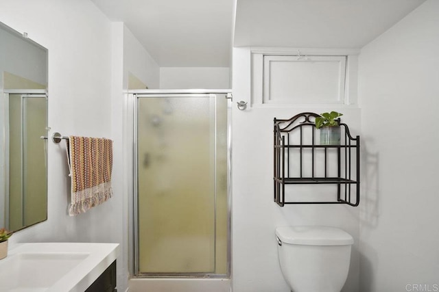 bathroom featuring a shower with door, vanity, and toilet