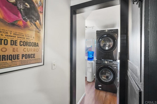 laundry room with hardwood / wood-style flooring and stacked washer / drying machine