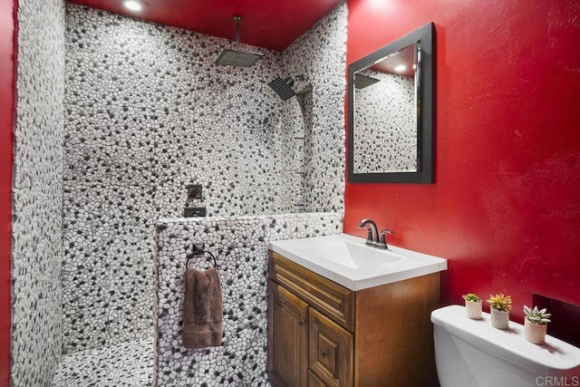 bathroom with toilet, a textured wall, a walk in shower, and vanity