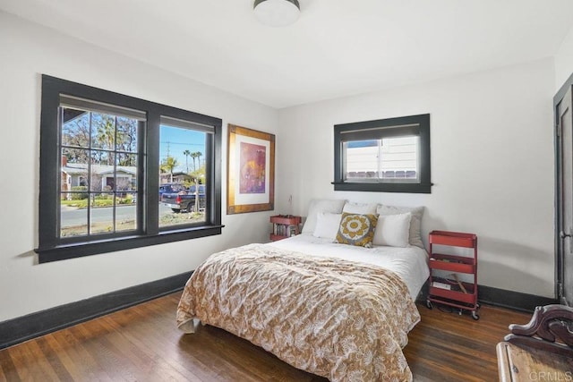 bedroom with dark wood-style floors and baseboards