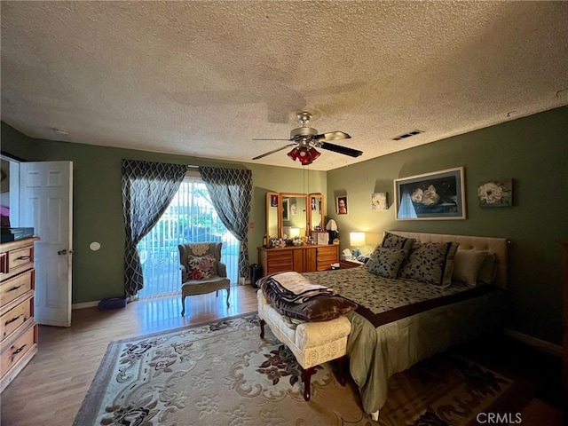 bedroom featuring ceiling fan, access to exterior, a textured ceiling, and light wood-type flooring