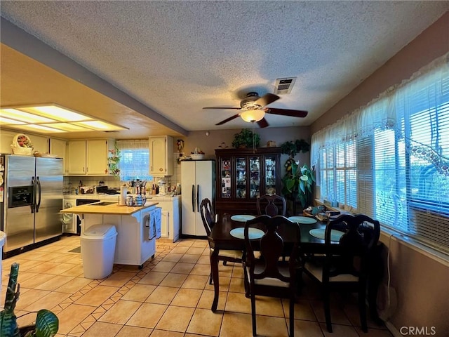 kitchen with light tile patterned floors, stainless steel fridge, ceiling fan, a textured ceiling, and refrigerator