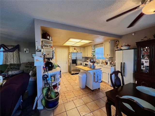 kitchen featuring stainless steel fridge with ice dispenser, white fridge, light tile patterned floors, white cabinetry, and a textured ceiling