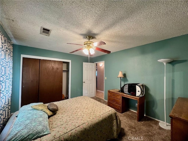 bedroom featuring ceiling fan, a closet, a textured ceiling, and carpet flooring