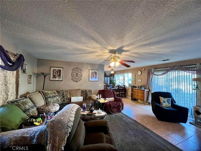 living room with a textured ceiling, ceiling fan, and light tile patterned flooring